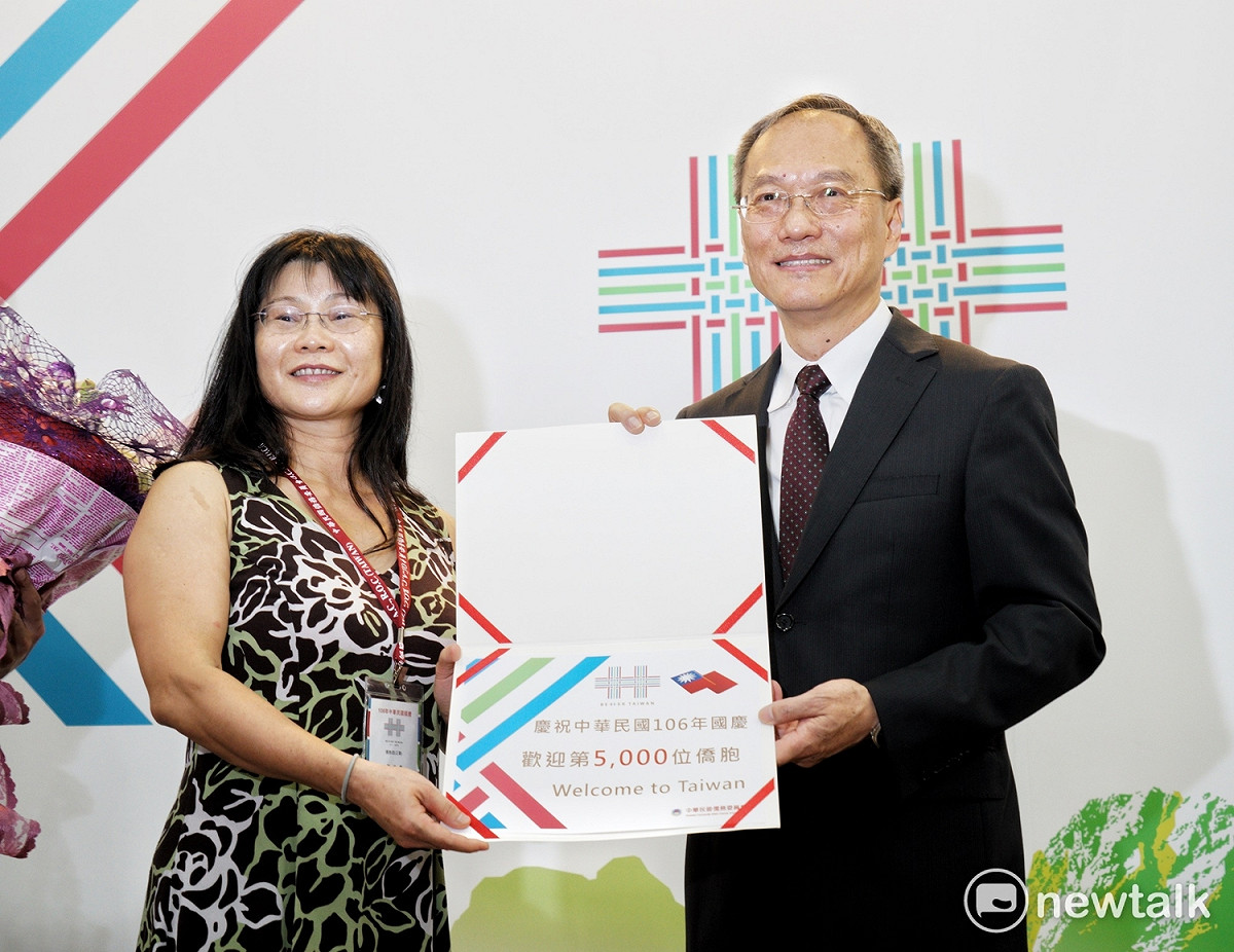 僑委會委員長吳新興將第5000位返國參加國慶大會的證書頒給來自美國洛杉磯地區的廖孟素小姐。 圖：張良一/攝