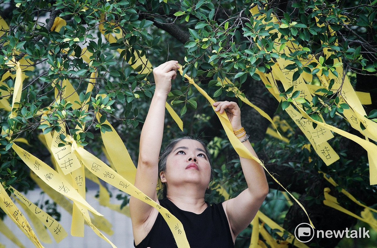 聲援團體成員在樹上繫上黃絲帶，表達對李明哲案與人權的關注。 圖：張良一/攝