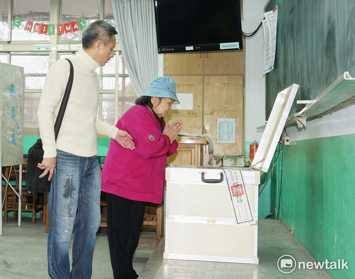 台灣民主政治史上頭一遭的黃國昌罷免案今投票，支持罷免黃國昌的孫繼正帶著母親去投票，而她的母親在投完票後，對著投票櫃雙手合十祈禱。 圖：張良一/攝