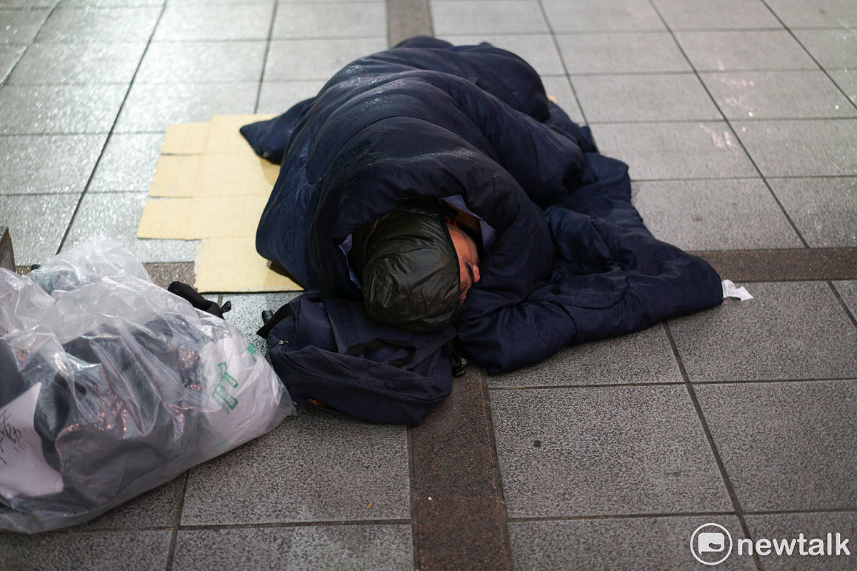 街友僅靠睡袋抵抗嚴寒雨夜。 圖：張良一/攝