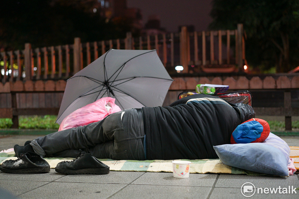 街友用雨傘遮風擋雨，再把棉被或是睡袋和身上所有的禦寒衣物全裹住身體，希望能抵抗這波強烈寒流。 圖：張良一/攝
