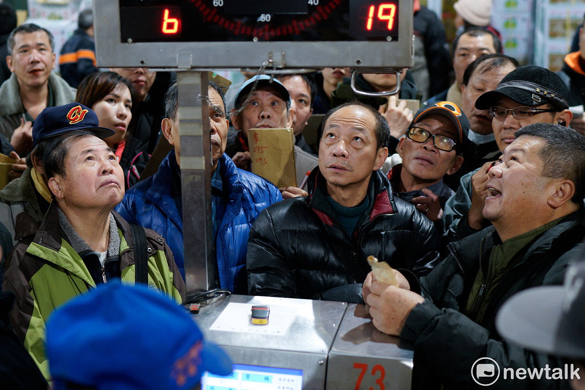 蔬果承銷人眼睛緊盯、專注的看著拍賣告示版的蔬果資訊。 圖：張良一/攝
