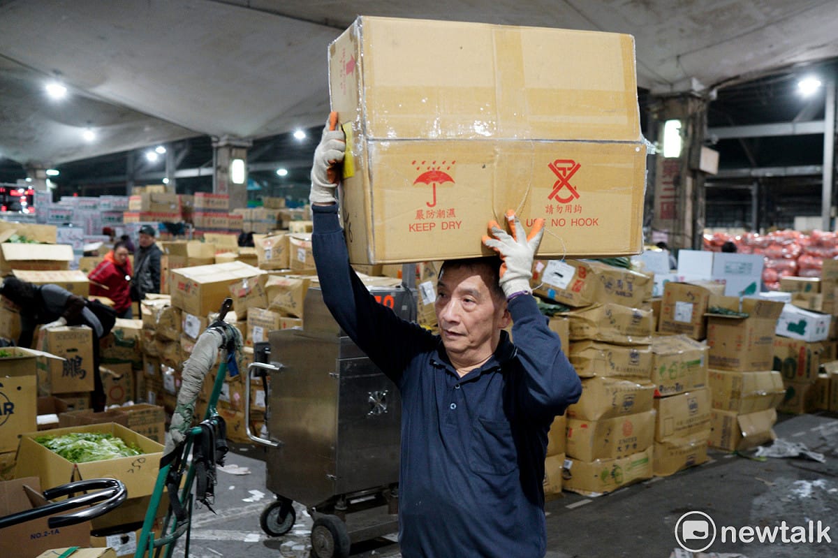 由於果菜市場內各式各樣的蔬果堆的滿地，人車又多，許多負責搬運蔬果的工作人員乾脆用頭頂著裝蔬果的箱子，以方便在擁擠的空間中，快速的將已標售的蔬果運送出去。 圖：張良一/攝