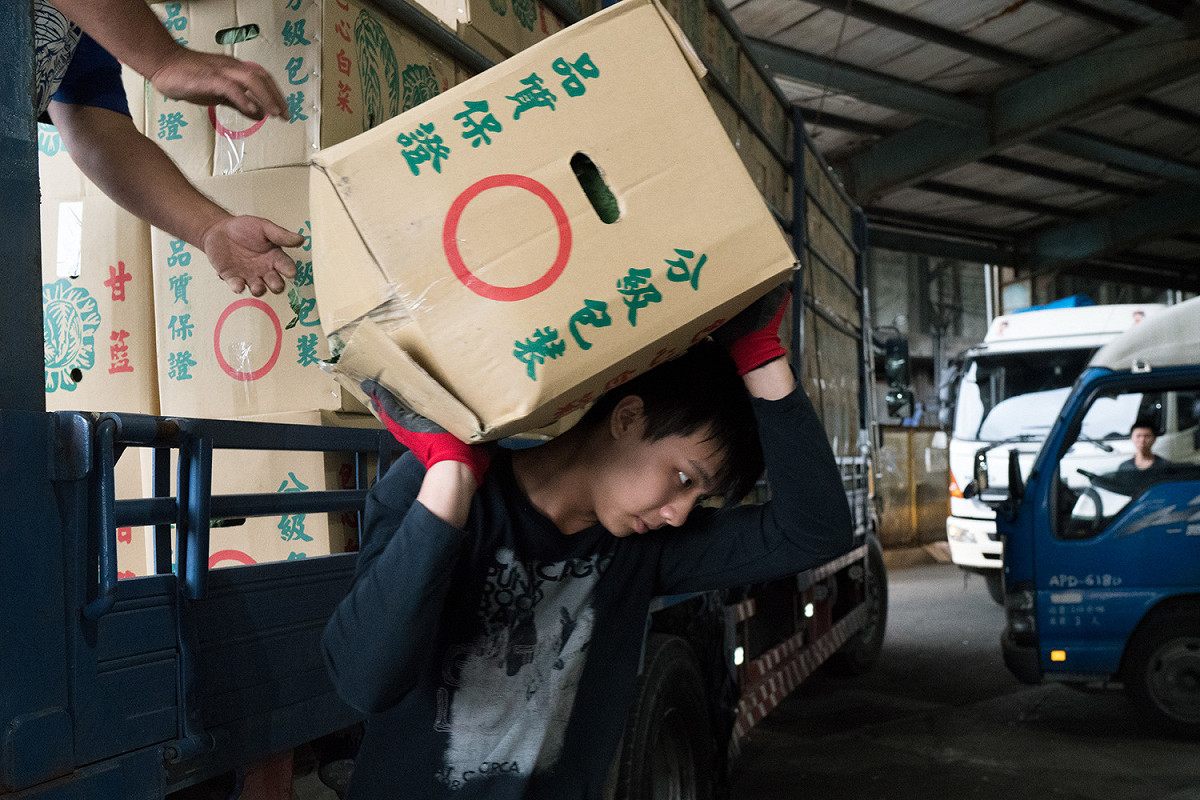 工作人員將一箱箱的蔬菜搬運下貨車 圖：張良一/攝
