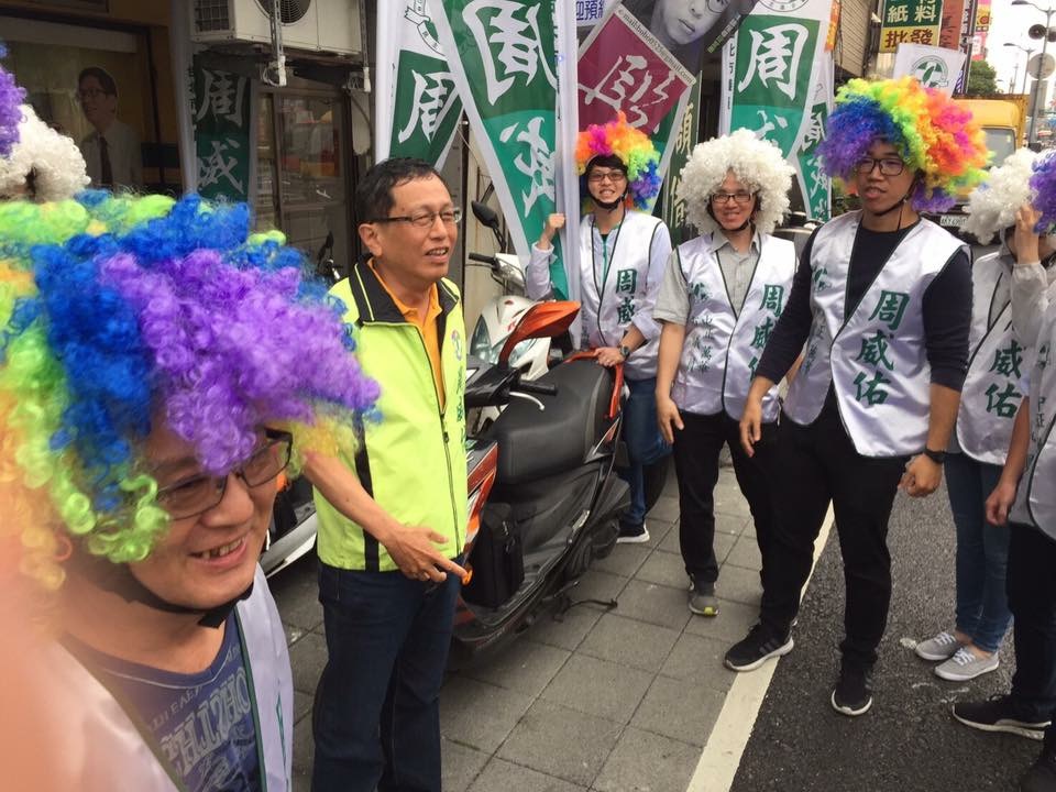 從政20年的民進黨市議員周威佑，節省成性，用段宜康10年前競選立委的爆炸頭的造型和道具，在街頭造勢。 圖：翻攝自周威佑臉書