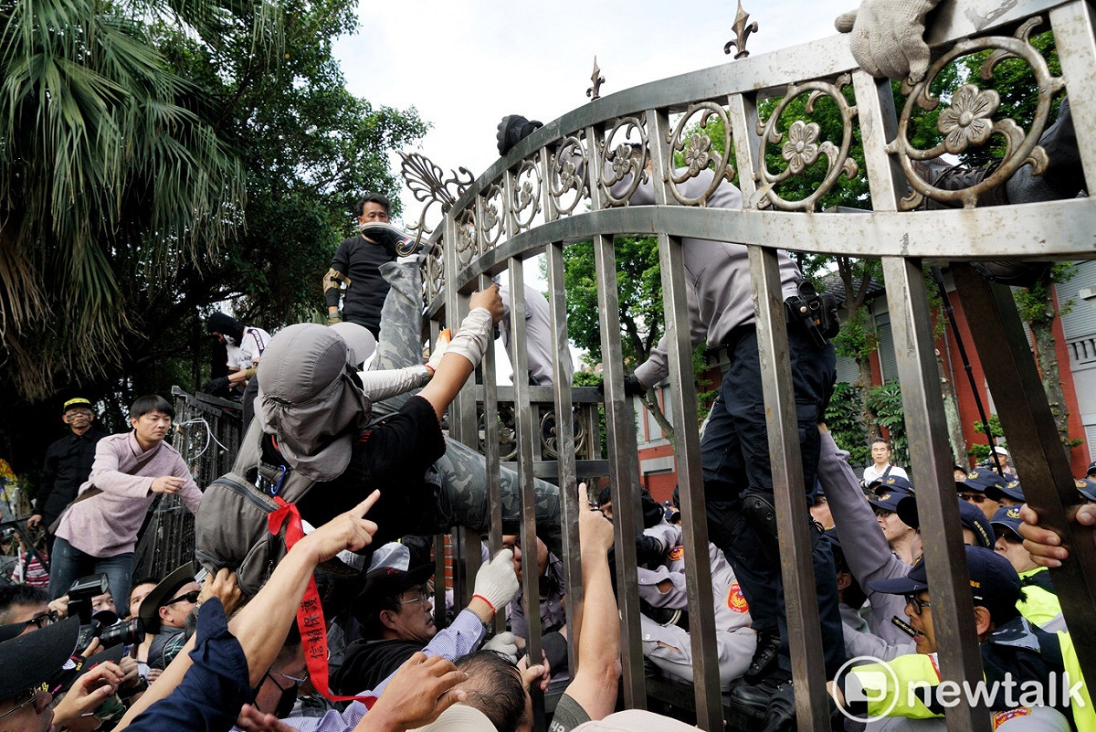 反年改人士與警方在鐵門上拉扯。 圖：新頭殼資料照片（張良一/攝）