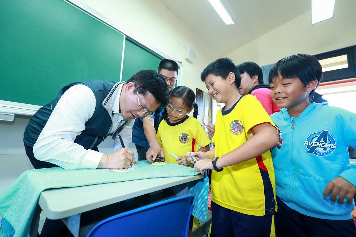 台中市長林佳龍視察西屯區東海國民小學校舍冷氣安裝，學生們請市長在簿子上簽名 ( 107/10/04 ) 圖：台中市政府/提供