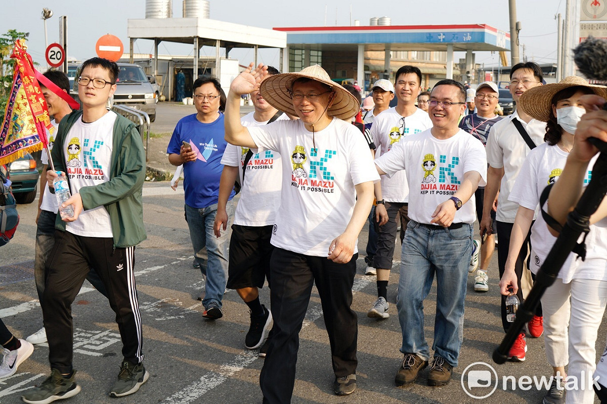 柯文哲參加大甲媽祖遶境活動，沿路時間太長，走在柯後面的幕僚，趁老闆揮手致意，以手勢調皮作弄一下老闆。 圖：張良一／攝影
