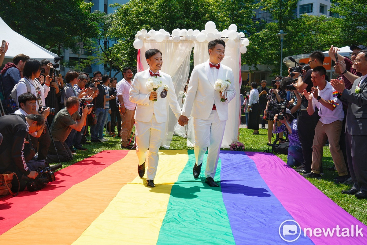 一對同性伴侶在信義區戶政事務所完成結婚登記後，一起走上彩虹地壇上。 圖：張良一/攝