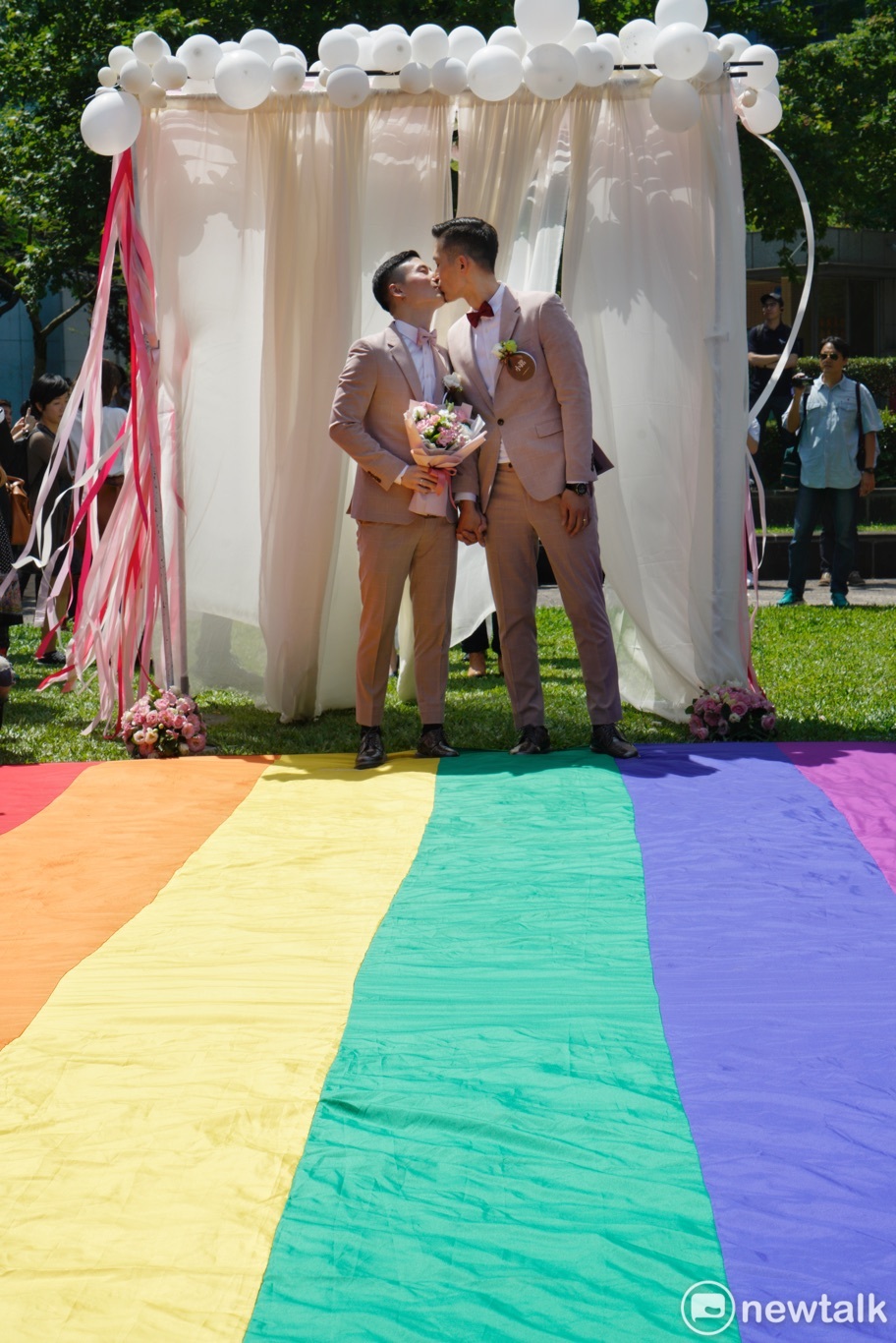 一對同性伴侶在信義區戶政事務所完成結婚登記後，在彩虹地壇上接吻。 圖：張良一/攝