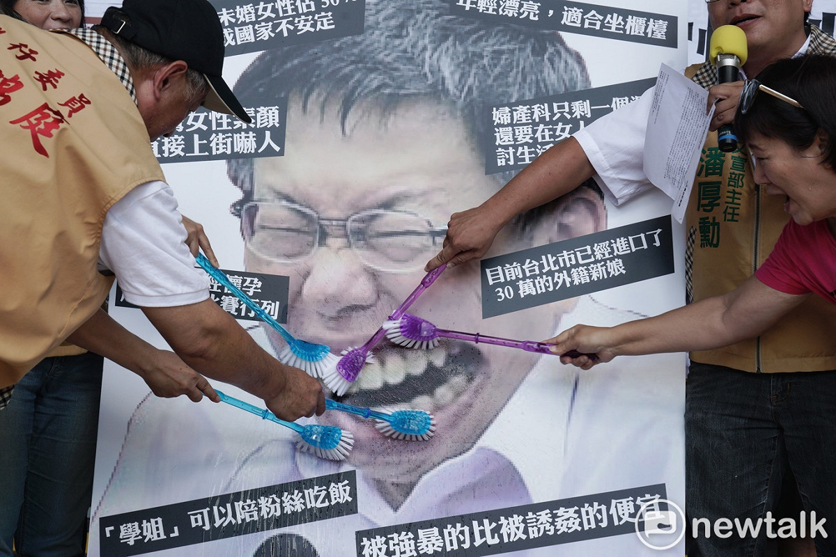 台灣團結聯盟成員在台北市政府前舉行的「請柯文哲管好市政、管好嘴巴」記者會中，用刷子刷柯文哲圖像中牙齒，藉此抗議柯文哲物化女性的諸多言論。 圖：張良一 / 攝