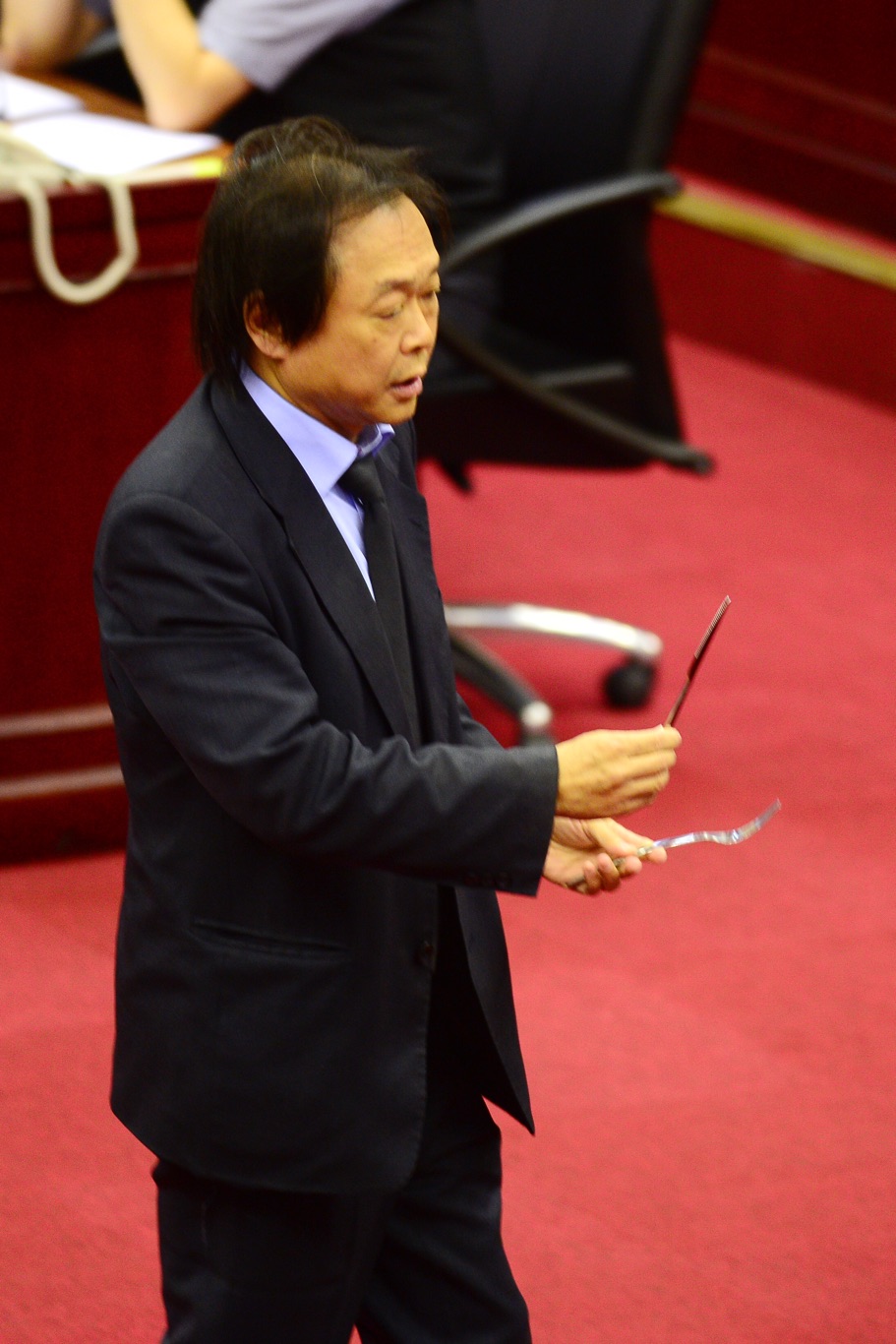 民進黨台北市議員王世堅在議場拿出刀叉，指台北市長拿刀叉吃人肉，吃人夠夠。 圖：張良一/攝