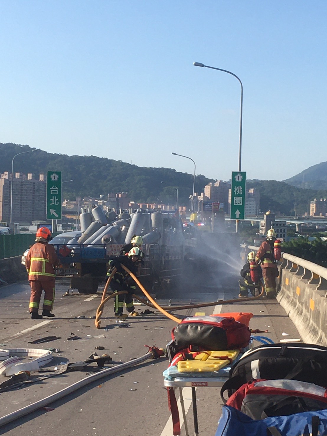 1538快速道路65北上1K（板橋往五股出口前1KM），現場7台自小客車及載運瓦斯鋼瓶小貨車發生連環車禍，1台小貨車有漏油冒煙情形，已撒水降溫，目前新莊往五股2線道無法通行。 圖：新北市消防局/提供