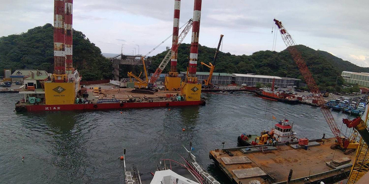 港務公司表示，宏禹1號平台船午後將直接靠泊漁具倉庫前碼頭，吊離豆腐岬側陸域兩塊橋面版及Y型鋼樑。 圖：台灣港務公司/提供