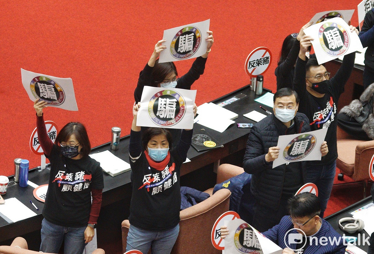 立法院院會今進行萊豬表決大戰，國民黨立委在民進黨立委發言人高舉民進黨騙的手舉牌反制。 圖：張良一/攝