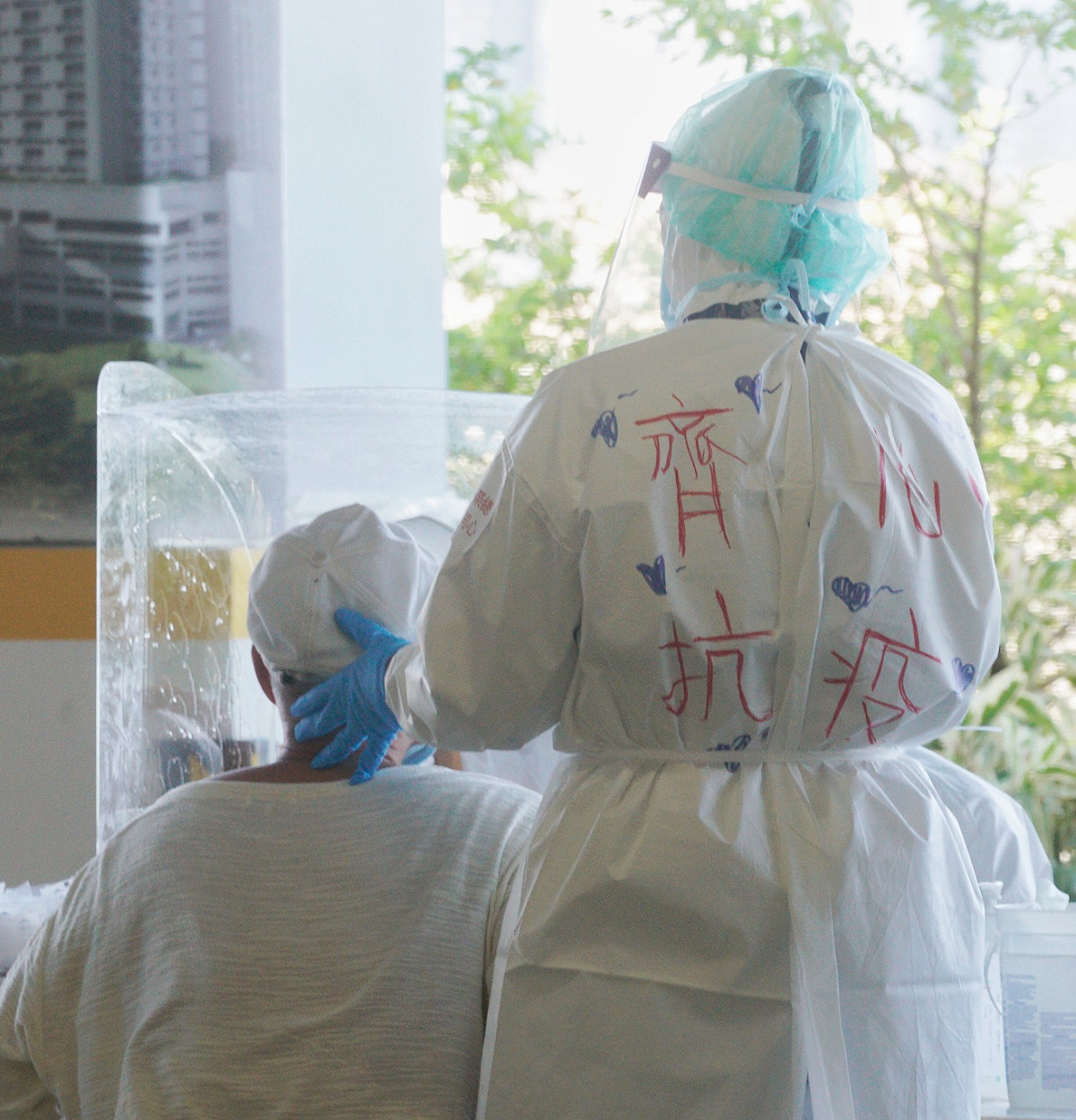 台北市府上午針對環南市台北市府上午針對環南市場有出現過確診者的漁產區、獸肉區！自治會以及附近里民，再進行一次大規模PCR篩檢，預計將篩檢近4千人。圖為一位榮總醫護人員在防護衣上寫上「齊心抗疫」。 圖：張良一/攝
