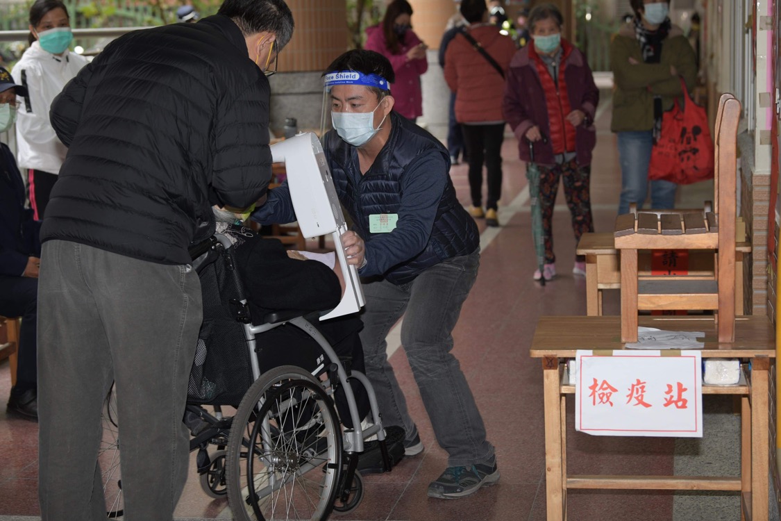 選務人員體貼的為來投公投票的民眾量體溫。 圖：張良一/攝