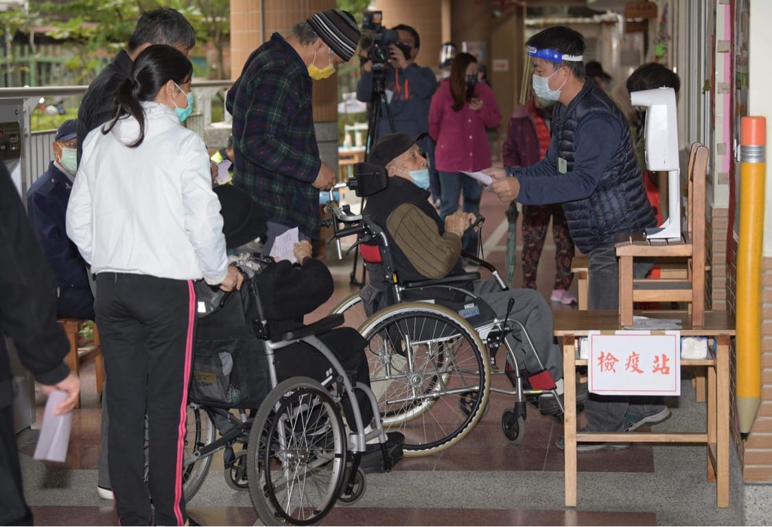 選務人員體貼的為來投公投票的民眾量體溫。 圖：張良一/攝