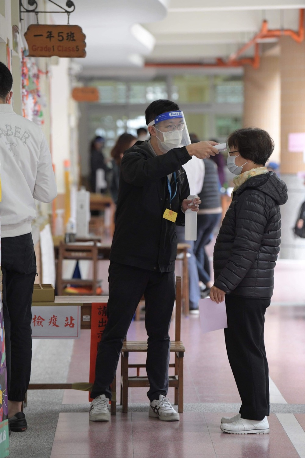 選務人員體貼的為來投公投票的民眾量體溫。 圖：張良一/攝