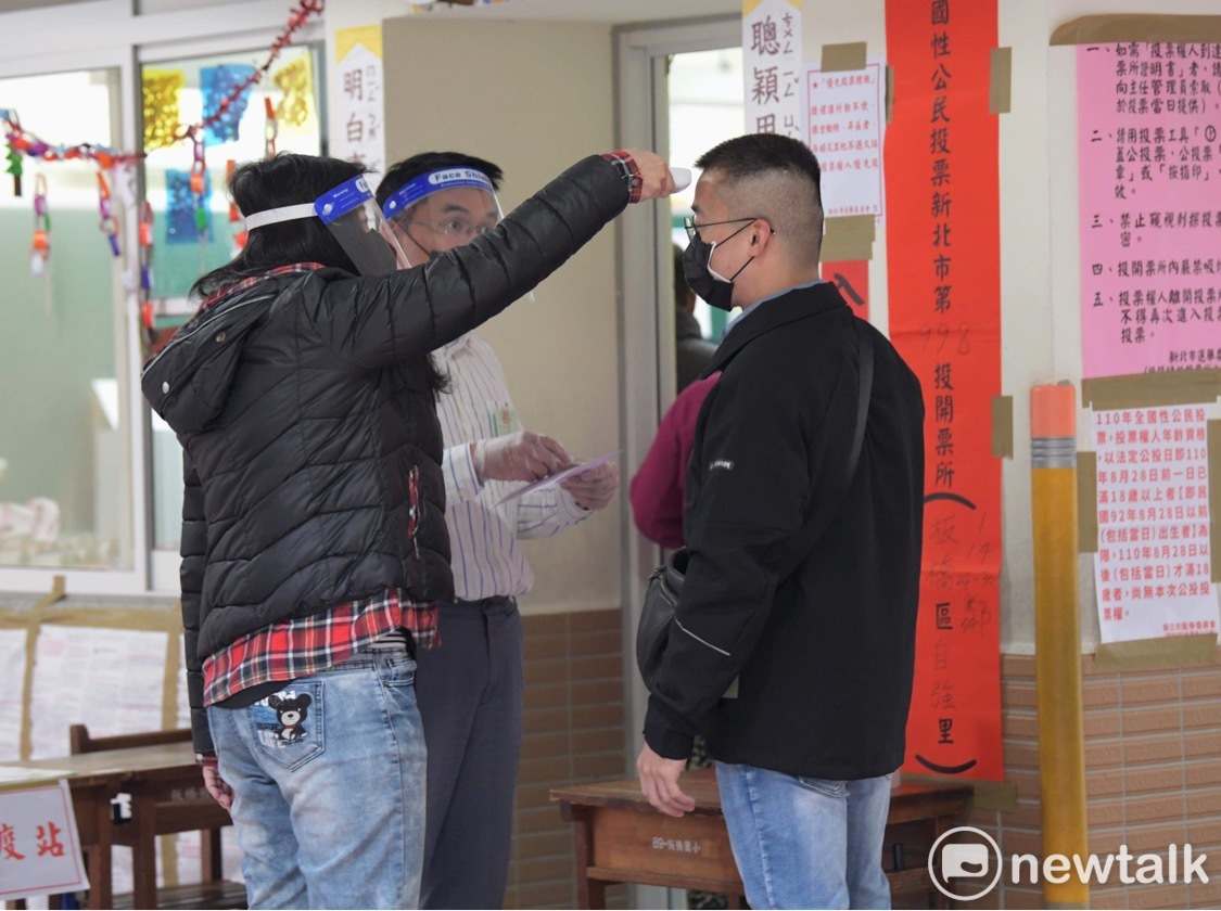選務人員體貼的為來投公投票的民眾量體溫。 圖：張良一/攝
