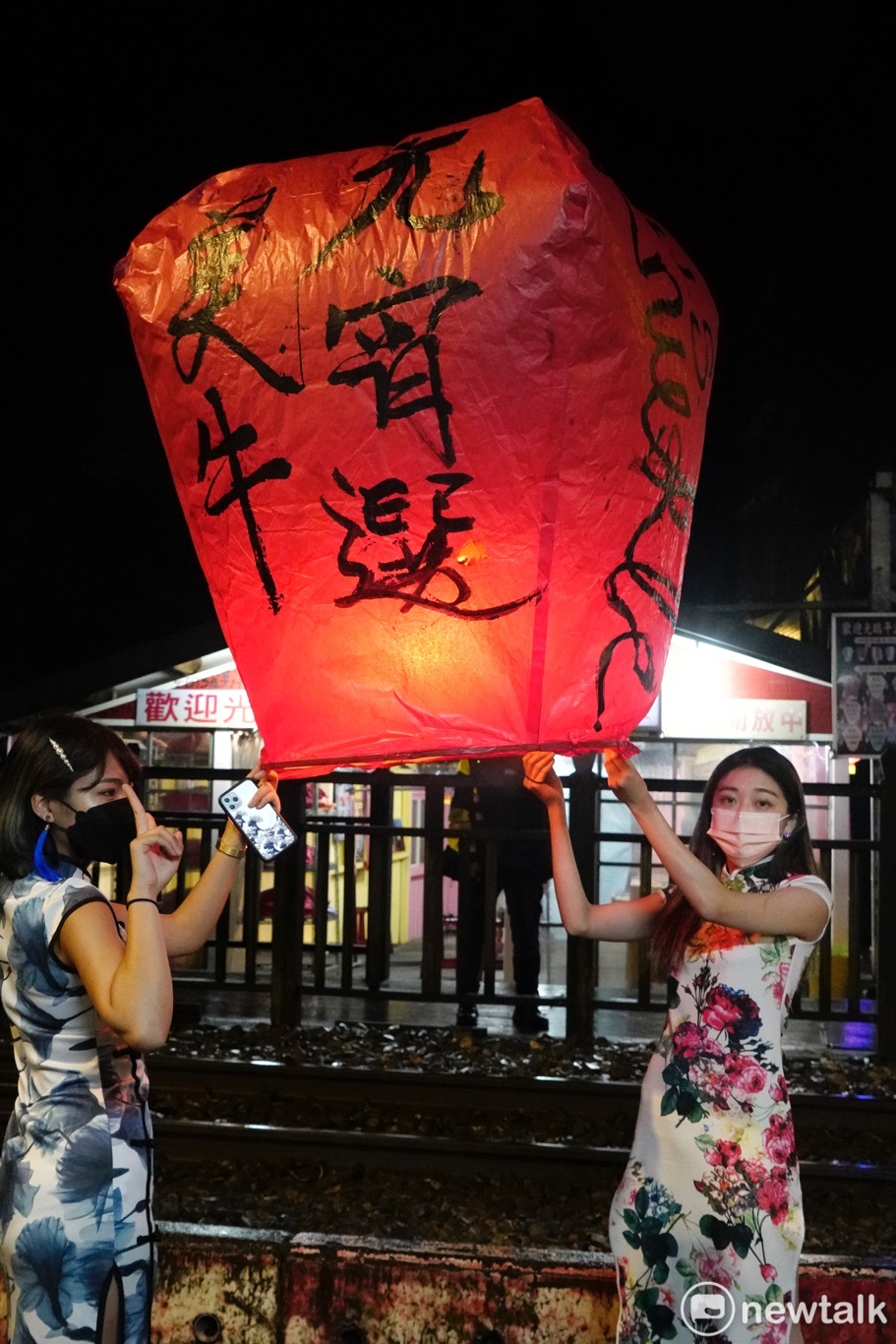 兩位民眾盛裝在平溪火車站旁放天燈。 圖：張良一/攝