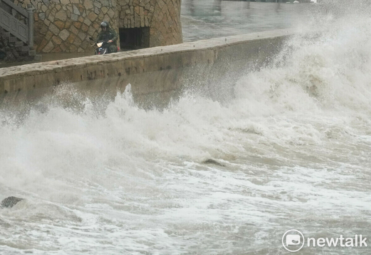 強烈颱風康芮來襲，馬祖東莒在十級陣風下捲起陣陣大浪並越過海堤。圖為一位一位東莒駐軍騎機車冒險經過海堤旁的道路。 圖：張良一/攝