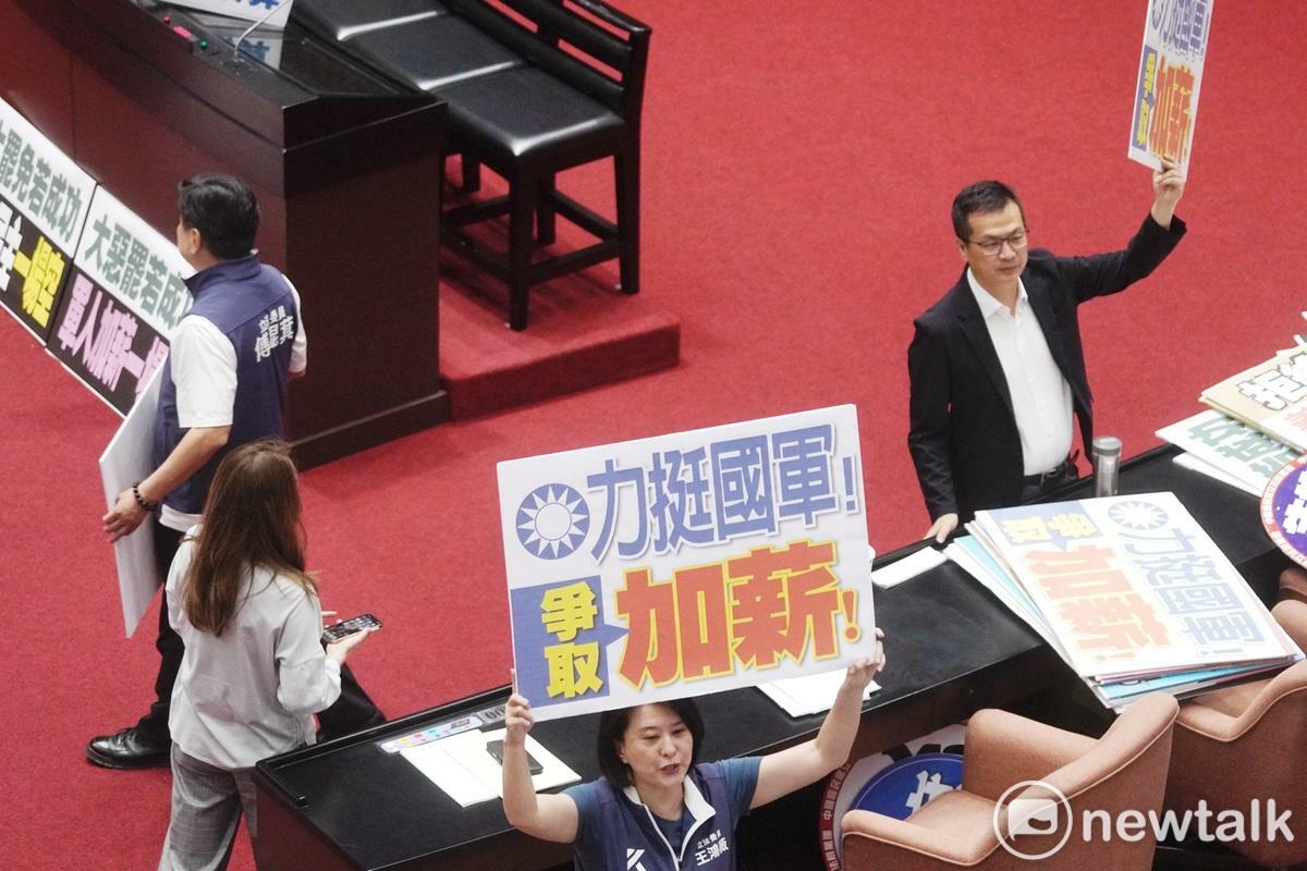 立法院長韓國瑜10日上午在院會敲槌三讀通過軍人待遇條例第五條，國民黨立委紛紛拿著力挺國軍加薪手舉牌在議場拍照。 圖：張良一/攝