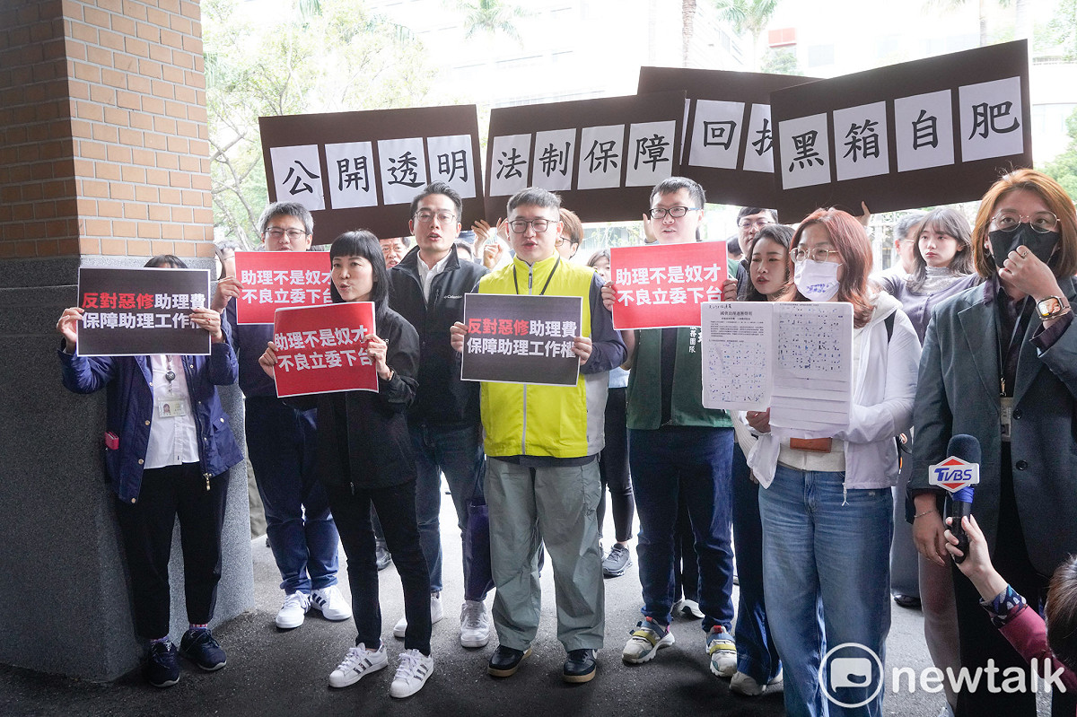 針對國民黨立委陳玉珍提案修修法「助理費除罪化」，立委院國會助理在立院大門口拉開白布條並高舉手舉牌呼喊口號，要求陳玉珍撤案。圖為陳玉珍到場和助理溝通時助理高舉手舉牌回應。 圖：張良一/攝