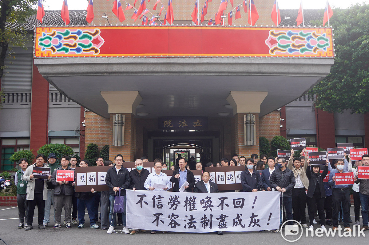 針對國民黨立委陳玉珍提案修修法「助理費除罪化」，立委院國會助理在立院大門口拉開白布條並高舉手舉牌呼喊口號，要求陳玉珍撤案。 圖：張良一/攝
