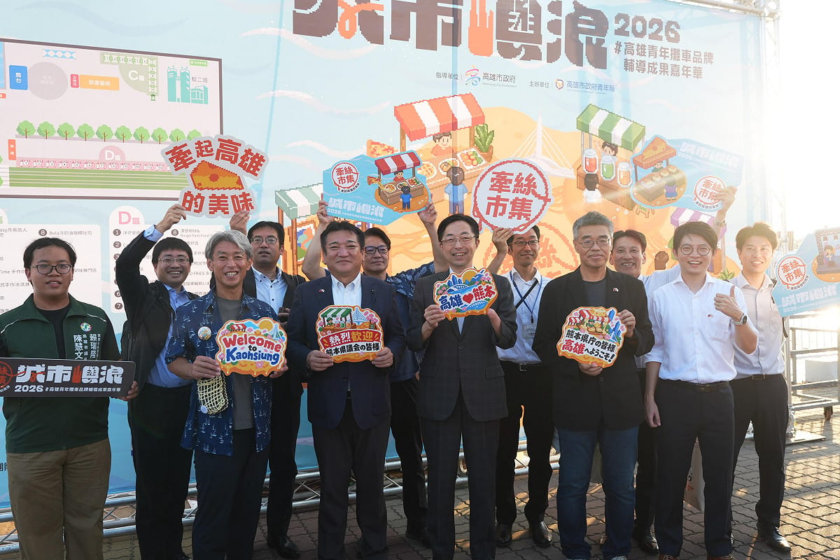 木村敬（右六）、內野幸喜（左五）及溝口幸治（左三）等貴賓走訪「城市嶼浪」，由李懷仁（右四）與林楷軒（右二）陪同於「牽絲市集」打卡牆前合影。 圖：高雄市政府青年局　提供