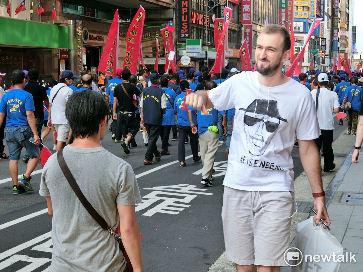 一名老外對著統促黨遊行宣傳車比喝倒采的手勢。 圖：李書璇/攝