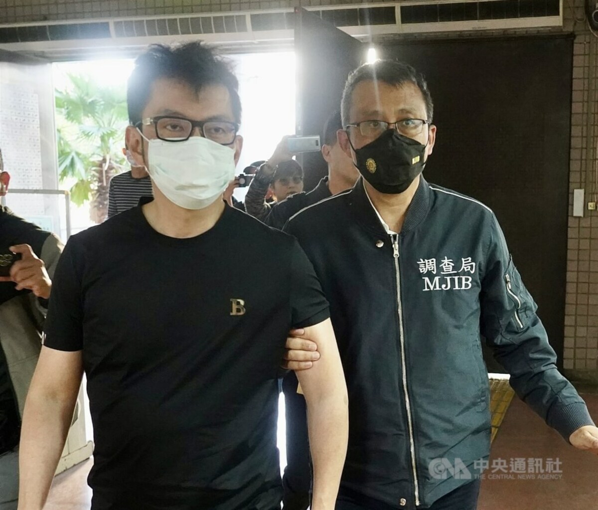 津棧公司出售含蘇丹紅的辣椒粉等產品，圖為李姓實際負責人（左）去年3月12日被調查局人員帶回畫面。（中央社檔案照片）