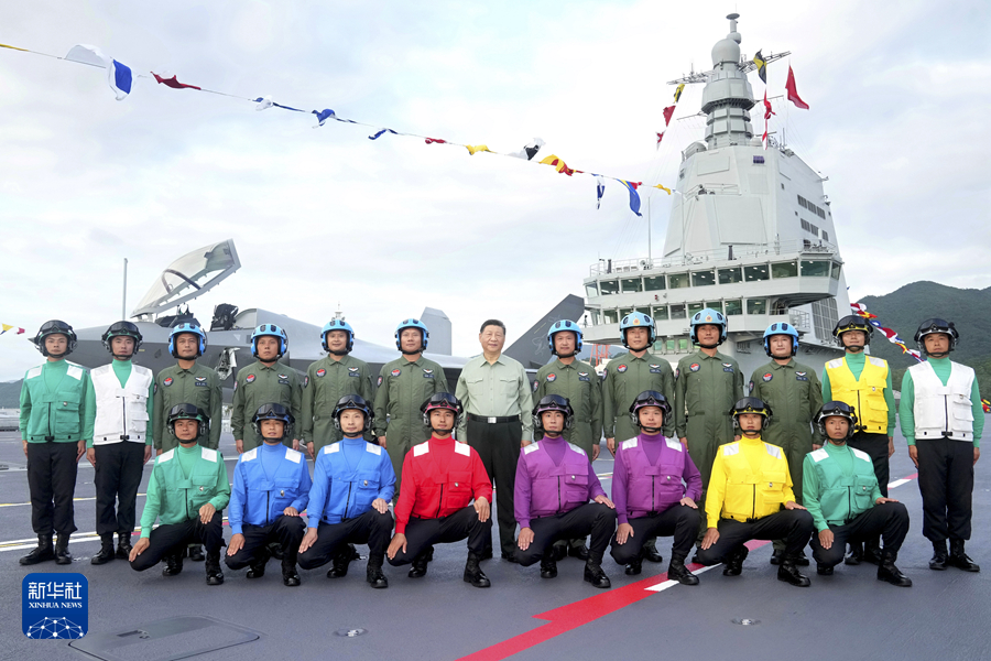 中共國家主席習近平在福建號飛行甲板與飛行員、航勤人員合影。背景是殲-35戰機。 圖：翻攝新華社