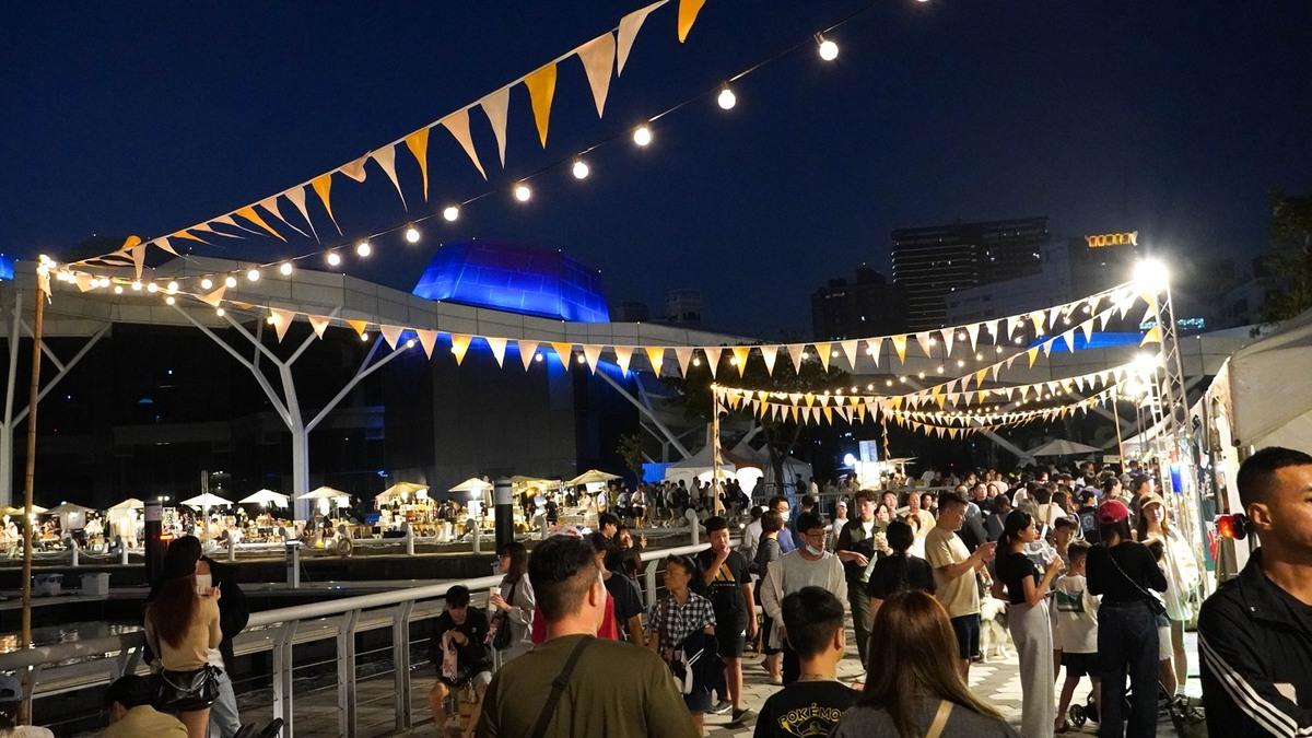 夜幕下的「城市嶼浪」市集燈火通明，民眾漫步愛河灣畔，感受港都悠閒節奏與創意交織的迷人夜色。 圖：高雄市青年局/提供