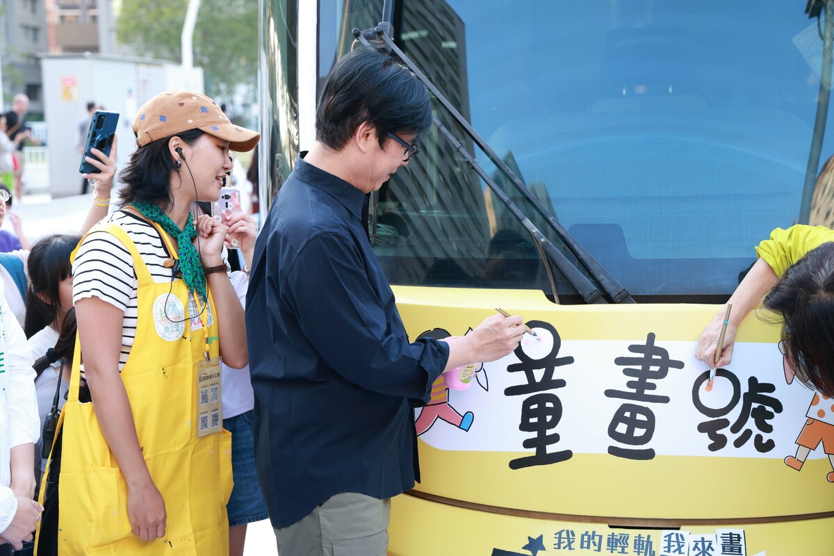 陳其邁(左二)在車頭畫上象徵歡笑的最後一筆。 圖：高雄市政府/提供