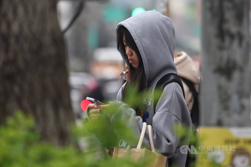 氣象專家吳德榮表示，24日晚起東北季風增強，北台灣氣溫下降。圖為新北市土城區外出民眾穿起連帽上衣禦寒。（中央社檔案照片）