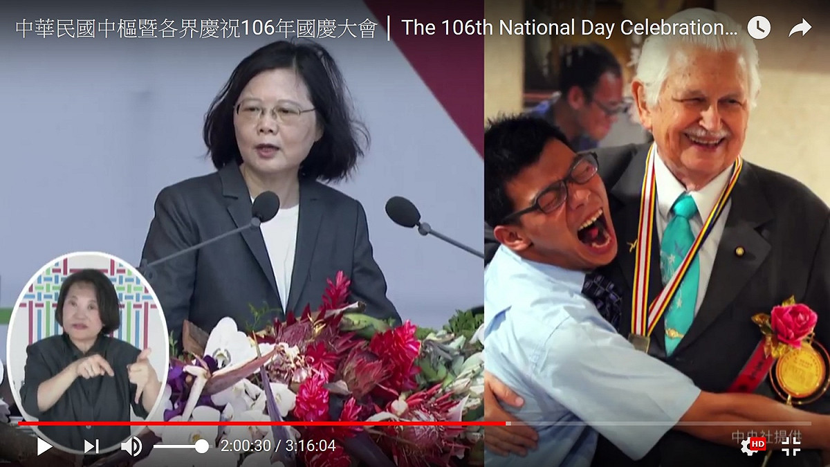 總統蔡英文10日國慶演講時，一旁的螢幕也播出甘惠忠神父畫面。 圖：翻拍自總統府直播畫面