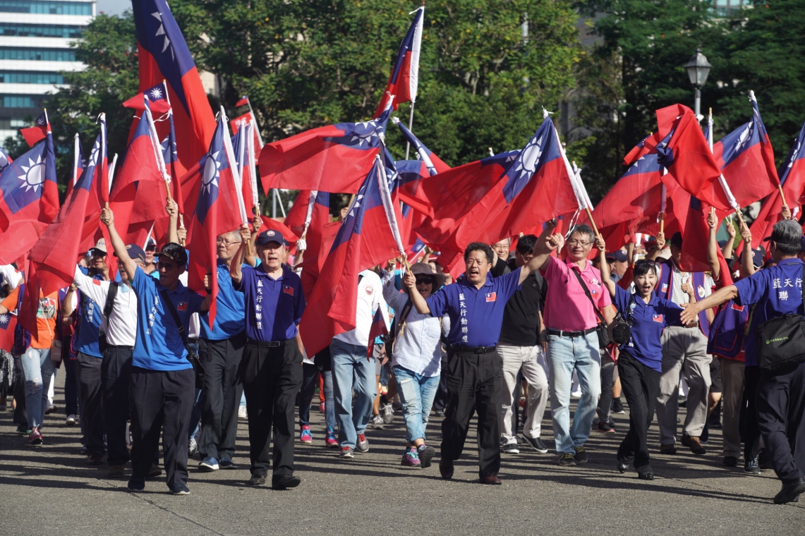 與會民眾高舉國旗，慶祝國慶。 圖：張良一/攝