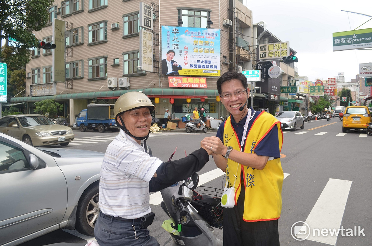 嘉義市長參選人李允傑18日懸掛選舉看板，為2018年選舉拉開序幕，他當場向路過民眾拉票。 圖 : 蔡坤龍/攝