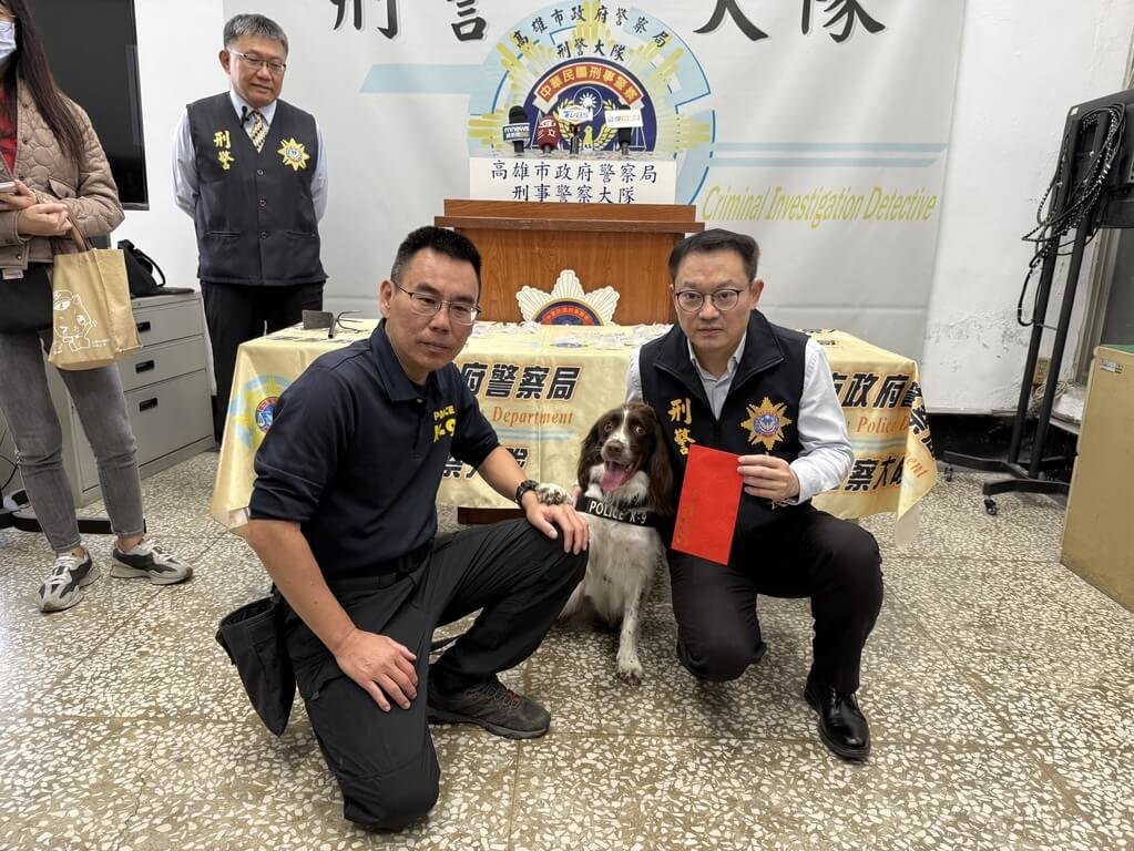 高雄警方查獲某販毒集團利用將毒品埋在偏僻公園，警方出動緝毒犬「可樂」（中）協助挖出192顆大麻菸彈，高市刑大大隊長鄢志豪（右）頒發加菜金給「可樂」。（高雄市刑大提供）中央社記者洪學廣傳真　114年12月12日