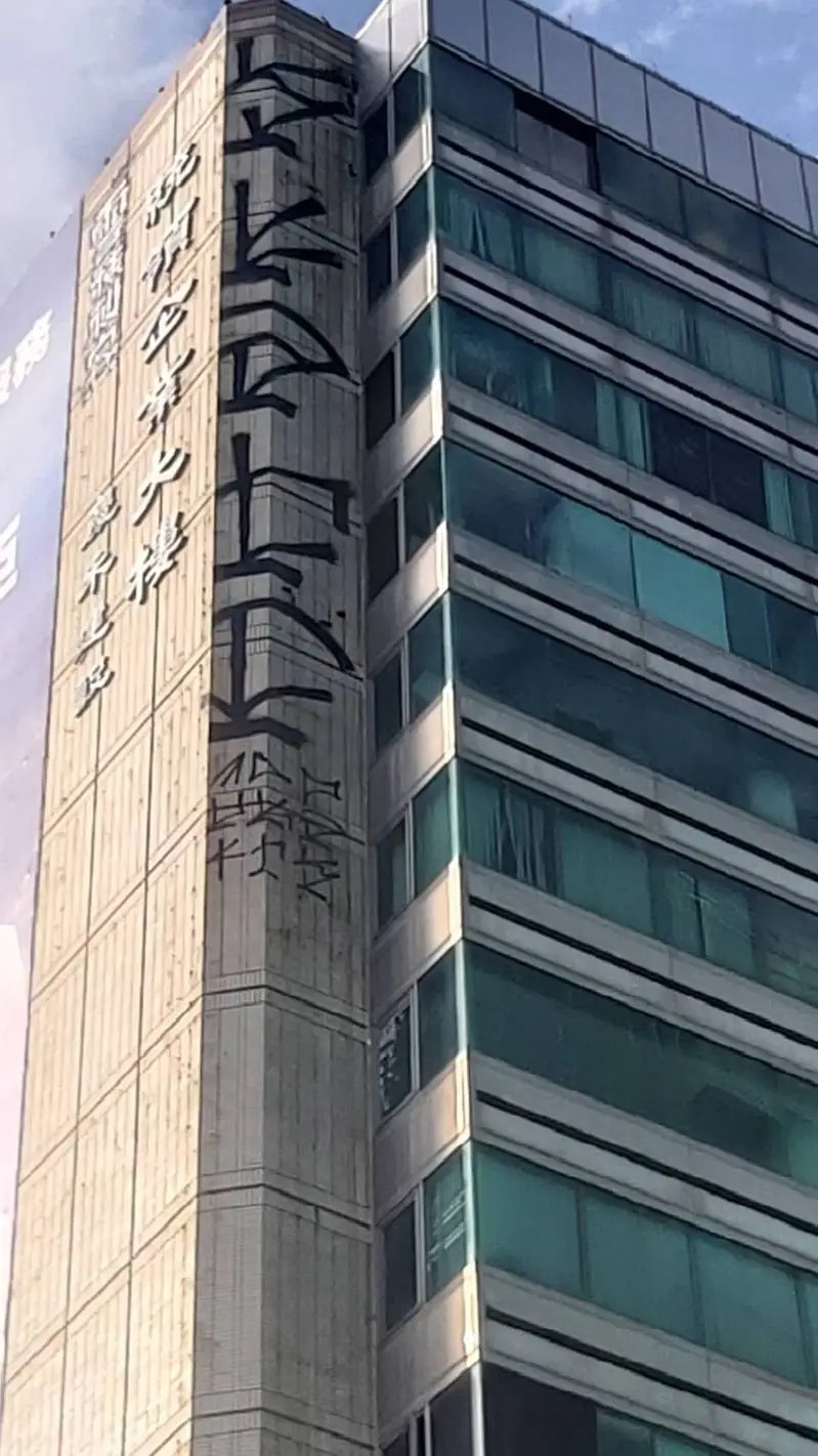 台中16層樓高的商辦大樓，外牆高處竟出現大面積塗鴉，還署名「雪糕刺客」。 圖：翻攝畫面
