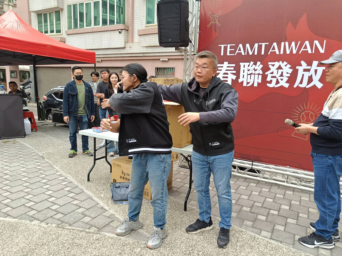 蔡其昌幫搶頭香的球迷穿上才自己身上脫下來的Team Taiwan外套。 圖：唐復年/攝