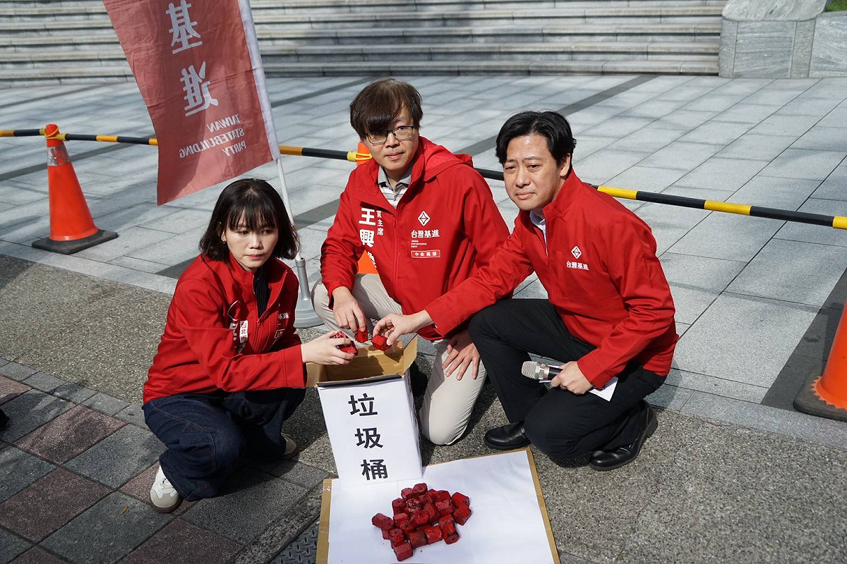 台灣基進於中天電視台前抗議，並將象徵「紅媒」的紅色煤炭丟入垃圾桶，表達抗議立場。 圖：台灣基進提供
