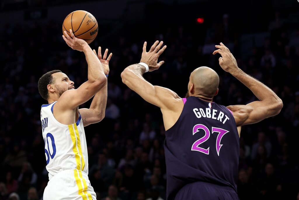 NBA勇士當家球星柯瑞（左）越過灰狼中鋒戈貝爾（右）防守出手投籃。（美聯社）