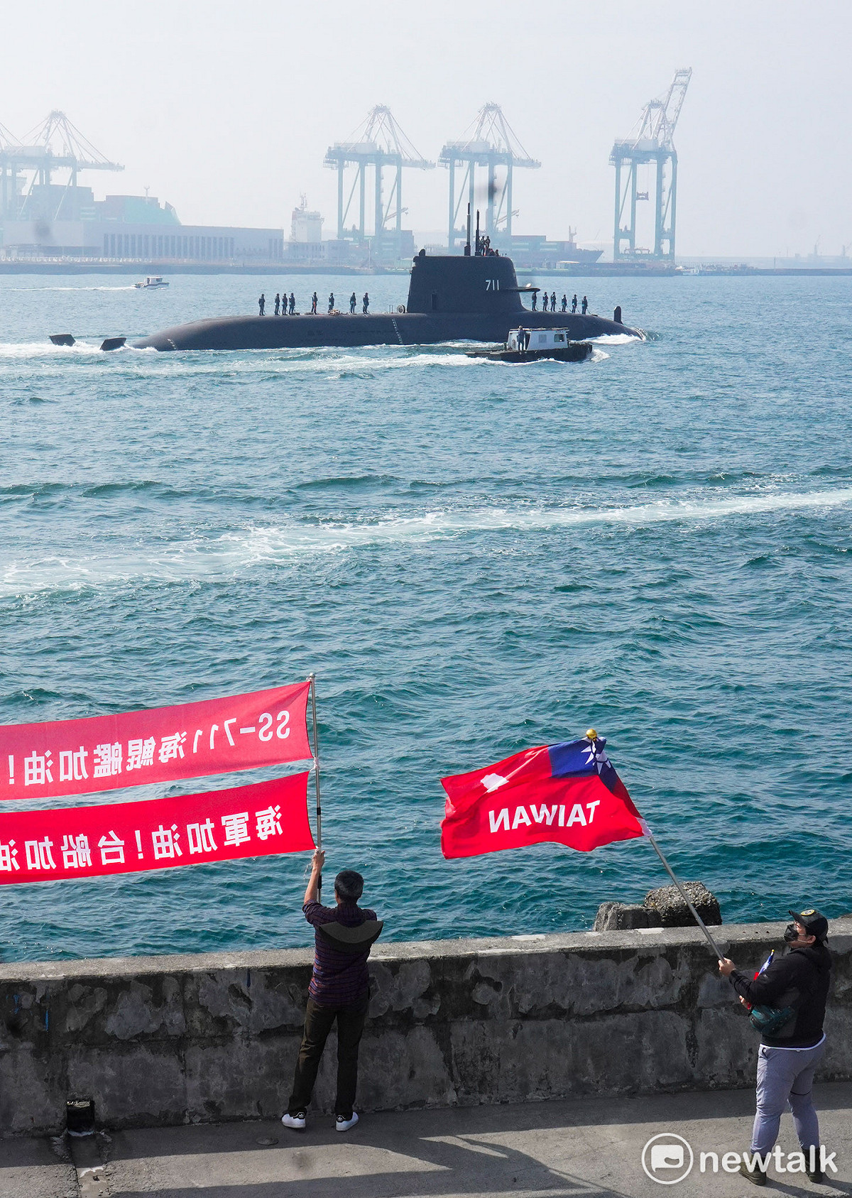 台灣首艘國造潛艦海鯤號今在高雄外海首度進行潛航測試，海軍退役官兵揮舞著書寫台灣的國旗為海鯤號出海潛航測試加油。 圖：張良一/攝