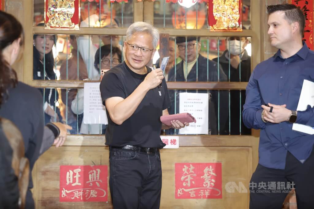 輝達（NVIDIA）執行長黃仁勳（中）31日晚間在台北宴請台灣供應鏈夥伴，在店外與粉絲互動時逗趣表示，幫粉絲簽錢包，那就得拿錢送給小孩子，或是交給店家當小費，隨後真的從錢包內拿出鈔票交給在場小朋友。中央社記者翁睿坤攝　115年1月31日 圖：中央社提供
