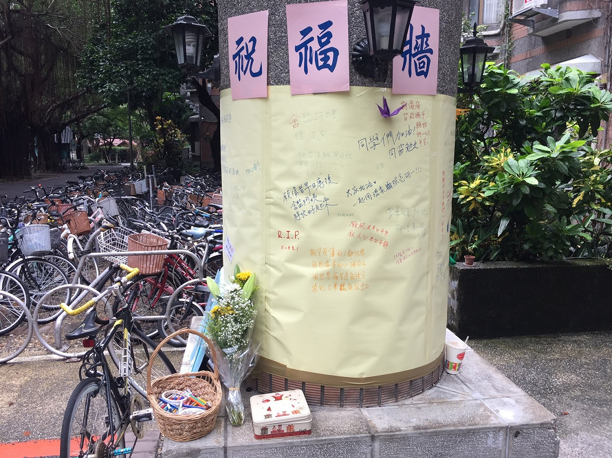 在案發地點女宿外的圓柱已經張貼巨大黃色海報，學生們在此寫下祝福話語、為傷者祈禱，希望校園早日恢復平靜。 圖：丘秝榕／攝