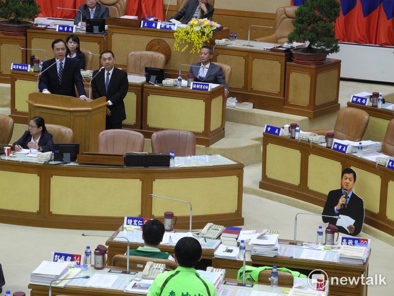 國民黨派誰參選新北市長？民進黨市議會黨團昨天擺出周錫瑋人形立牌，質詢朱立倫及侯友宜。 圖：王峻昌/攝