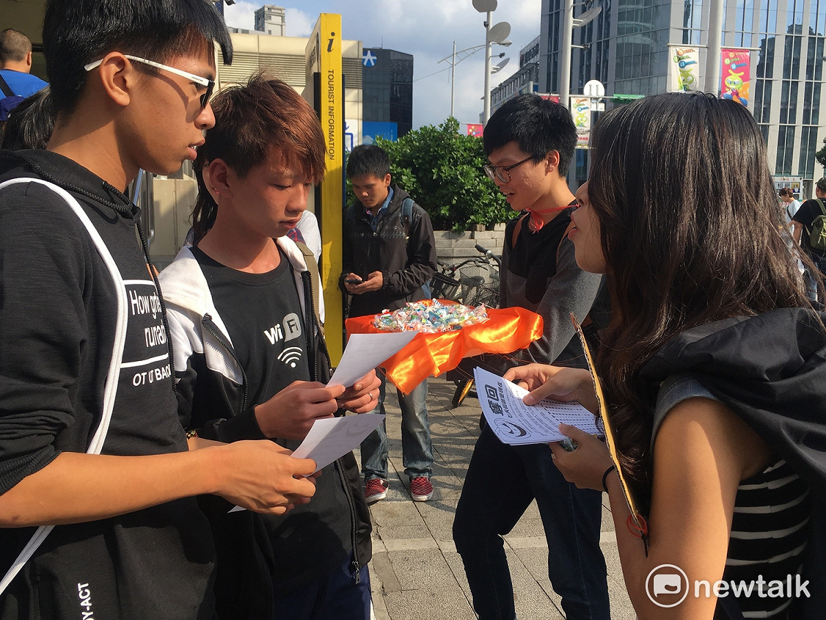 學生們沿路發放糖果給路人，介紹七天假與一例一休。 圖：黃韋銓/攝
