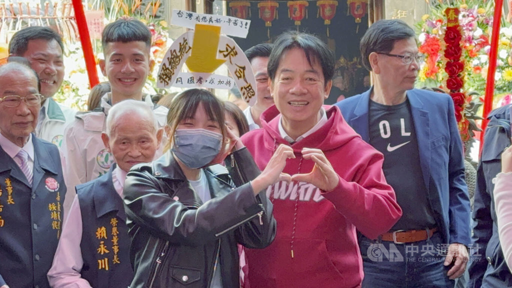 總統賴清德（紅衣者）17日到嘉義市城隍廟參拜祈福，隨後發放福袋給民眾，有民眾帶著自製道具與賴總統合照。 圖：中央社提供